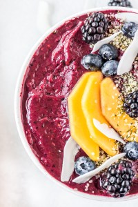 purple puree topped with fruit in white bowl